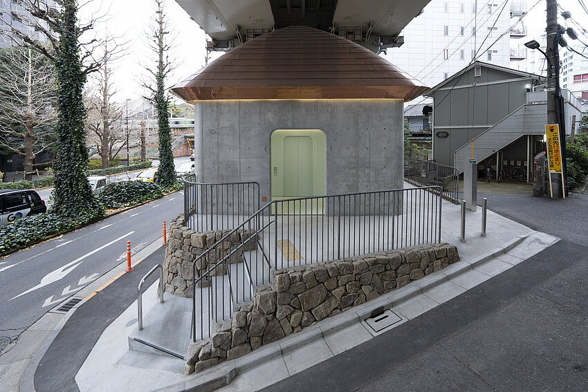 Exterior view of the toilet in Ursando. The house has concrete walls and a roof made of copper.